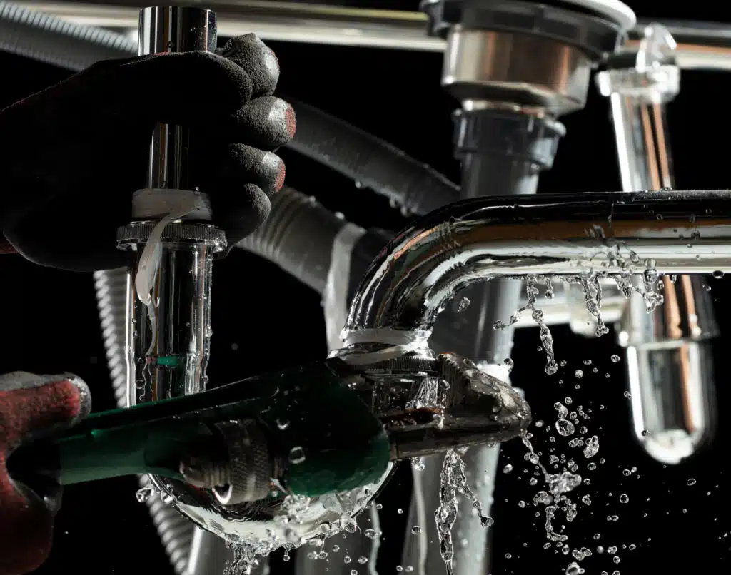 Plumbing Fixtures, Plumber used wrench to tighten loose nut on water drain pipe under kitchen sink.