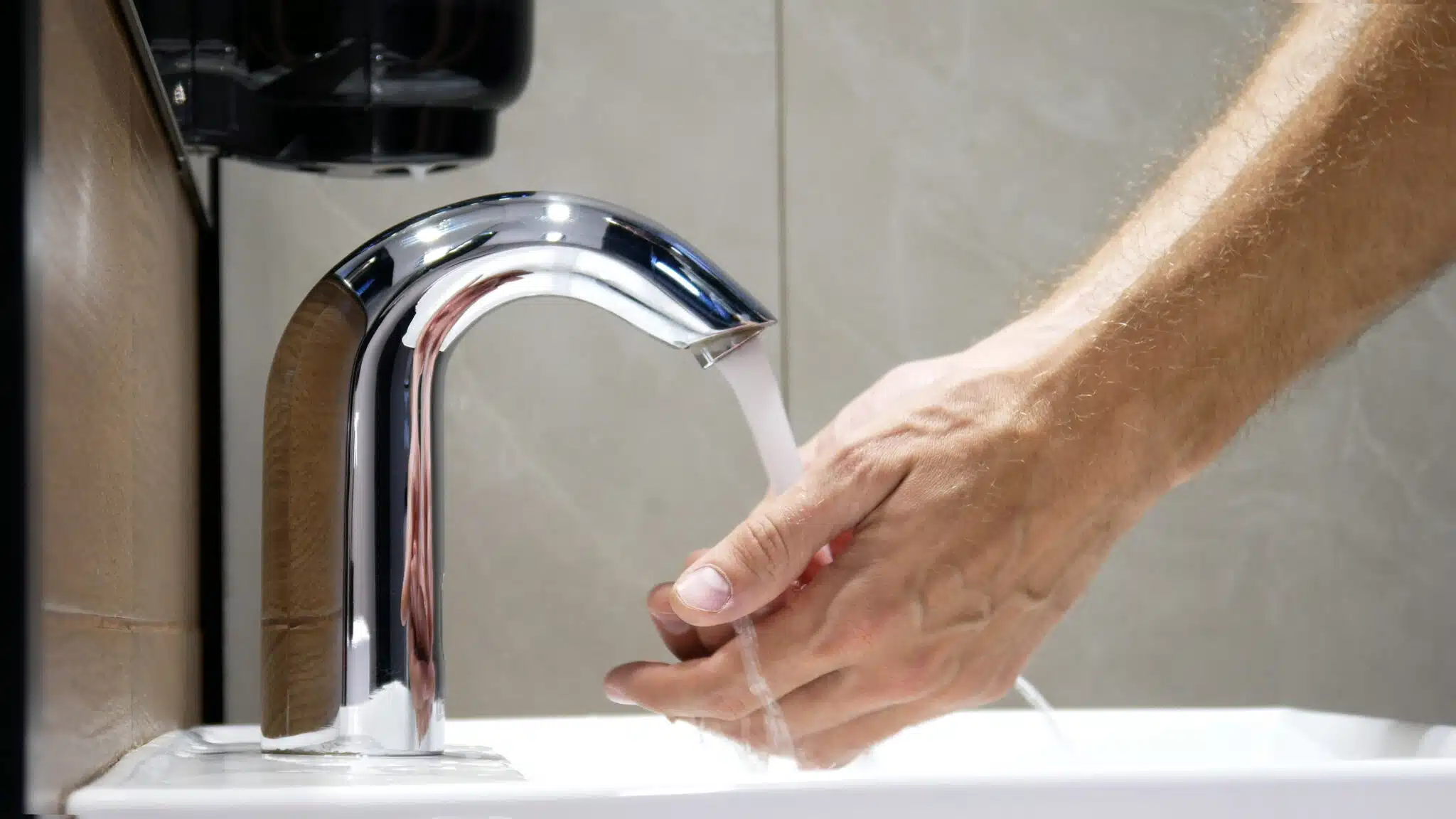 A man washes his hands using a touchless faucet close-up, Plumbing Technology Innovations.