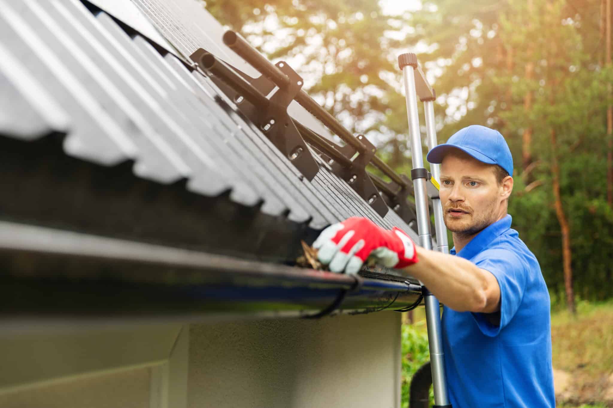 Worker cleaning house gutter from leaves and dirt, Plumbing News.